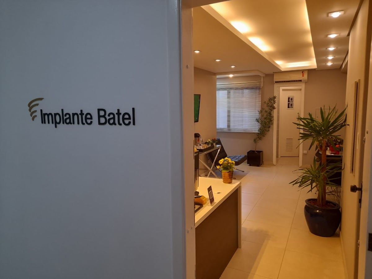 Recepção da Implante Batel com o nome da clínica na parede e a sala de espera ao fundo